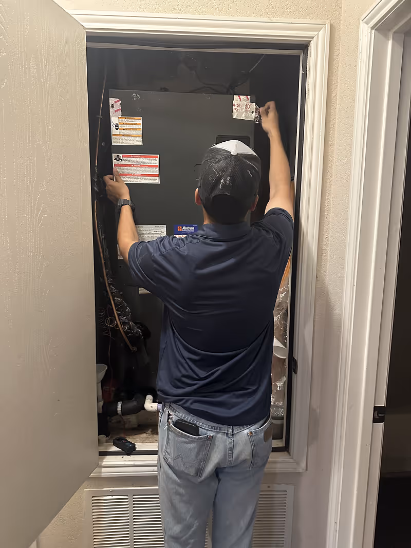 Technician installing or inspecting equipment inside a utility closet