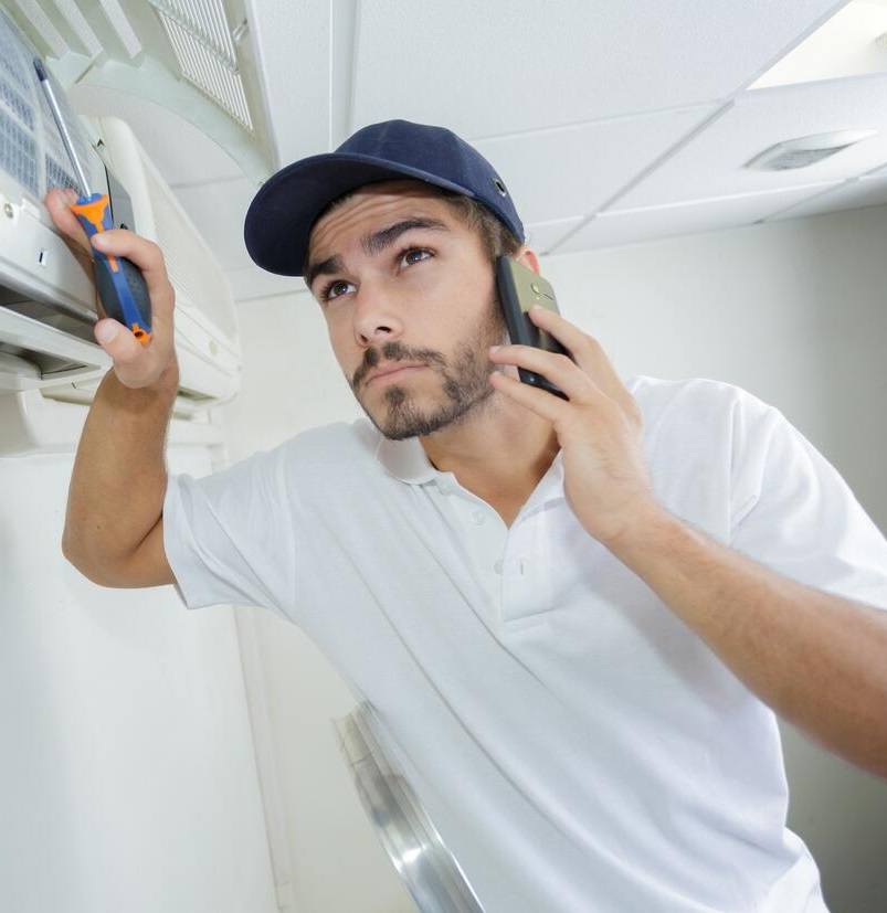 YOUNG HANDYMAN REPAIRING AIR CONDITIONING SYSTEM CALLING FOR HELP
